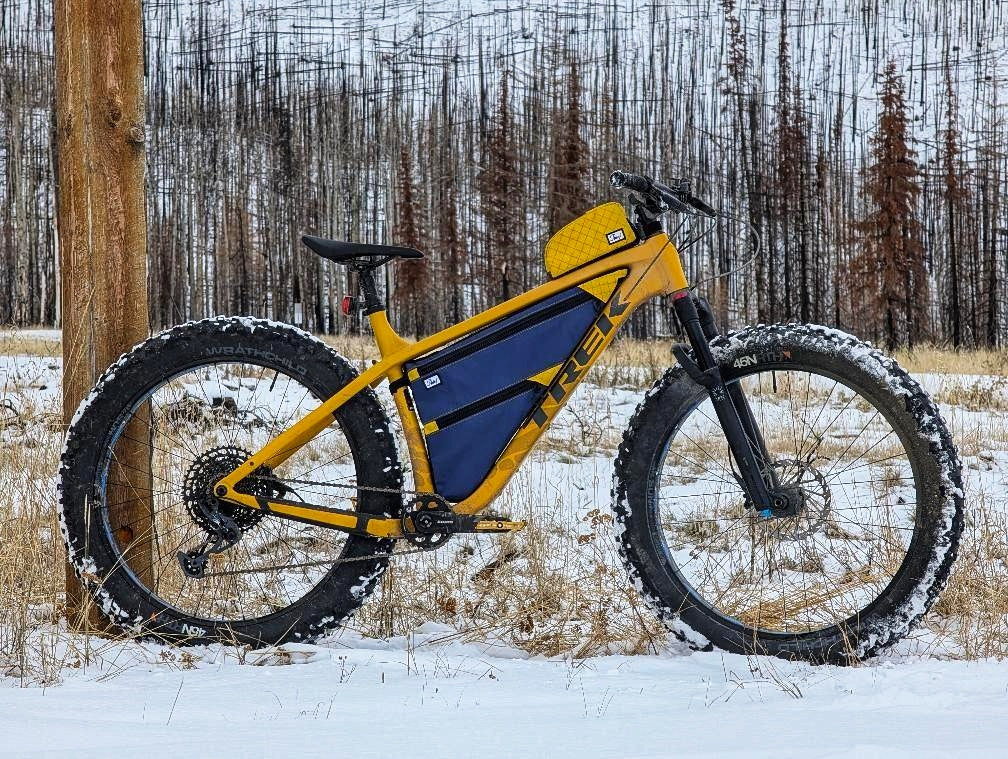 Yellow and blue bicycle with large tires in a snowy field.