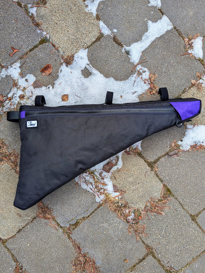 Black and purple bolt on frame bag on a stone pavement with snow patches