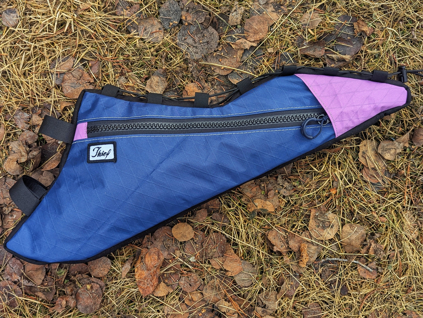 Blue and pink bag with a visible brand logo on a natural ground background
