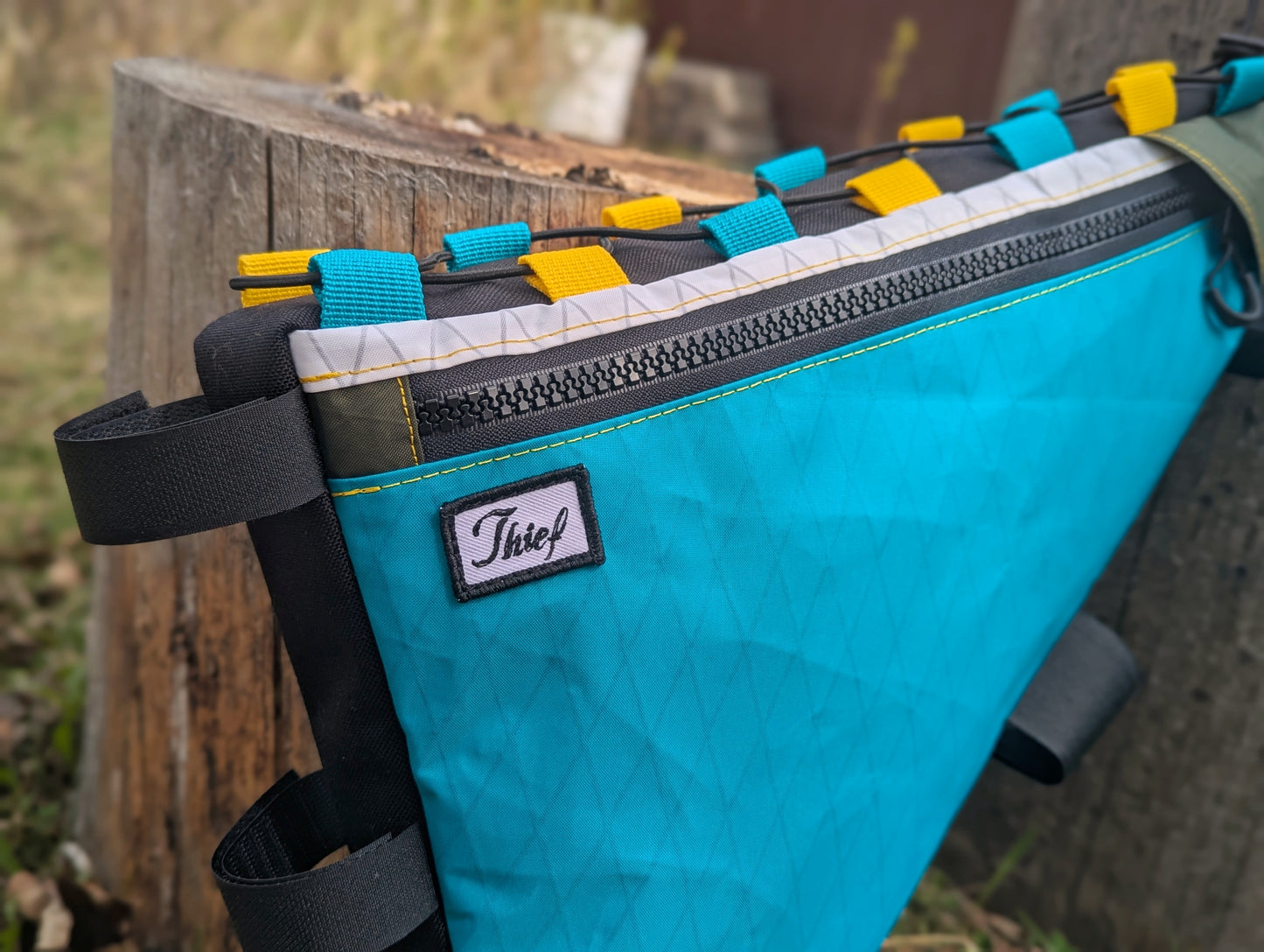 Teal bag with colorful straps attached to a wooden post outdoors