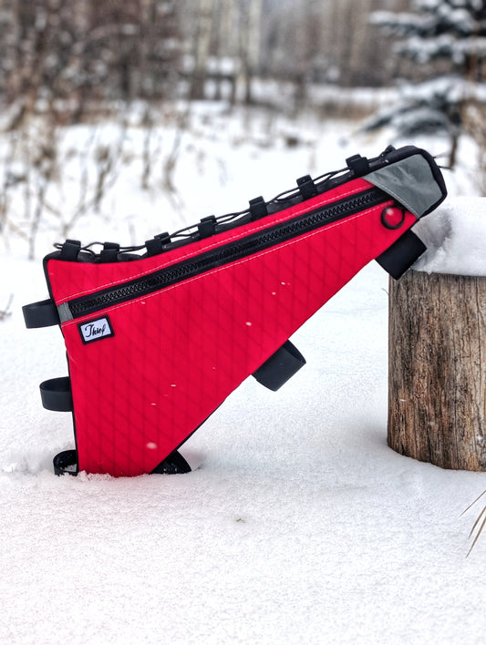 Red and black bag leaning against a wooden post in a snowy landscape